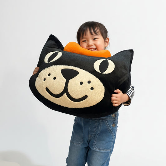 Child holding Jellycat Jack Giant Head plush toy, a cute cat-shaped cushion with a friendly expression.