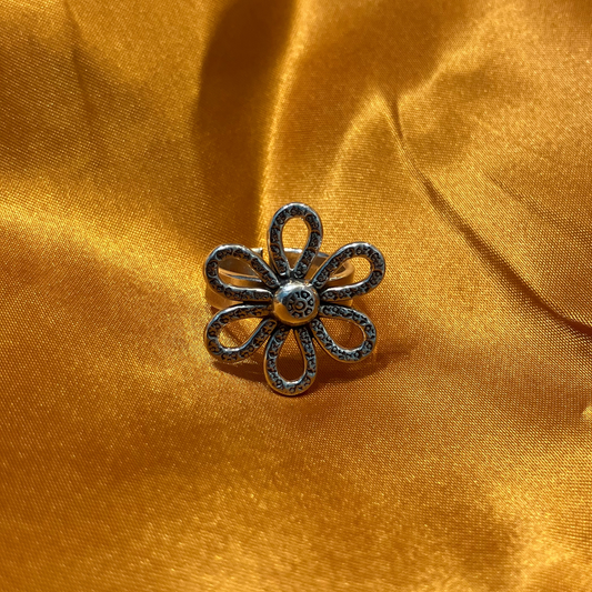 Handmade silver flower ring on golden fabric, adjustable and unique for everyday wear.